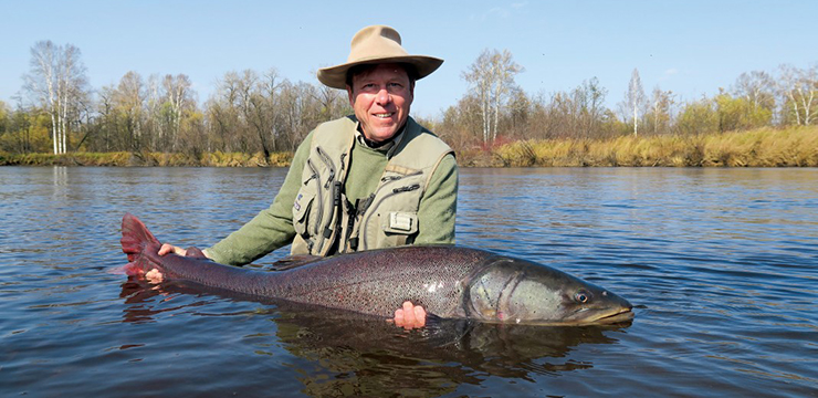 photo of Guido Rahr, standing in river holding salmon